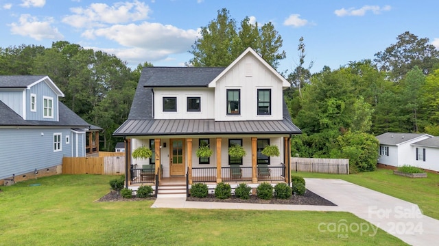 modern farmhouse style home featuring covered porch, board and batten siding, a standing seam roof, metal roof, and a front lawn