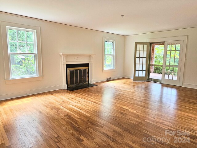 unfurnished living room featuring light hardwood / wood-style flooring, ornamental molding, and french doors