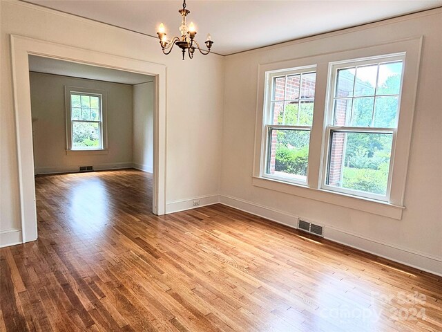 unfurnished room featuring light hardwood / wood-style floors and an inviting chandelier