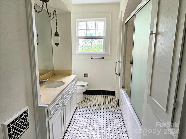 full bathroom featuring shower / bath combination with glass door, tile patterned floors, toilet, and vanity