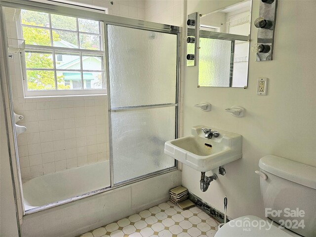 full bathroom featuring sink, bath / shower combo with glass door, toilet, and tile patterned flooring