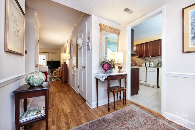 corridor featuring light hardwood / wood-style floors, a textured ceiling, and sink