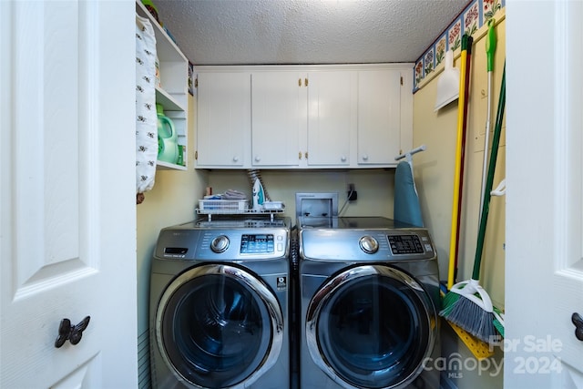 laundry area with cabinets, a textured ceiling, and washer and dryer