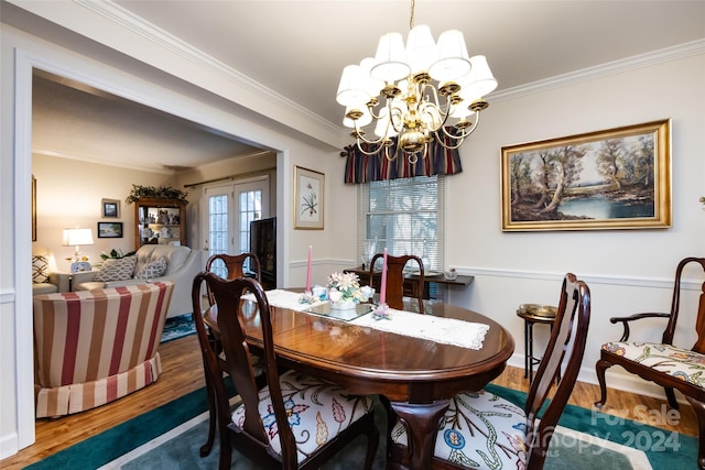 dining area with wood-type flooring, crown molding, a notable chandelier, and french doors