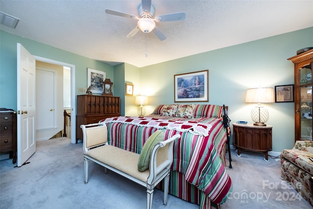 bedroom with a textured ceiling, ceiling fan, and light carpet