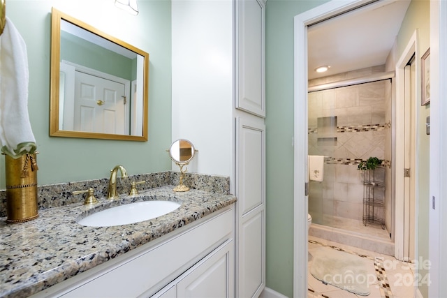 bathroom with a shower with door, vanity, and toilet