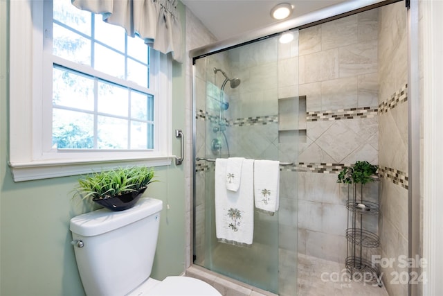 bathroom featuring toilet and a shower with shower door