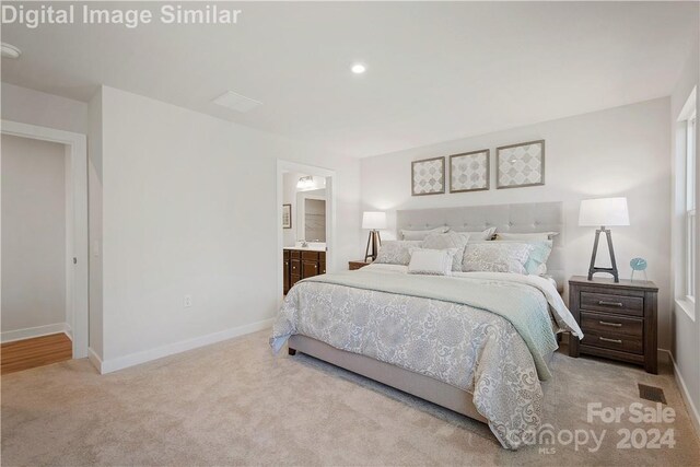 bedroom with ensuite bath and light carpet