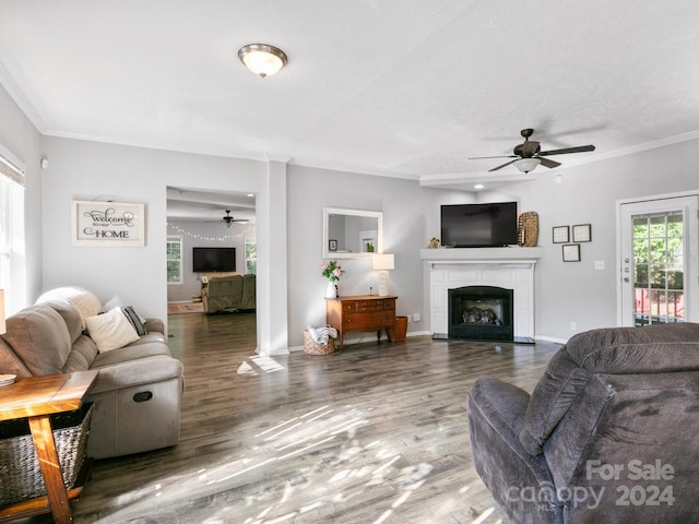 living room with a fireplace, ceiling fan, crown molding, and dark hardwood / wood-style floors