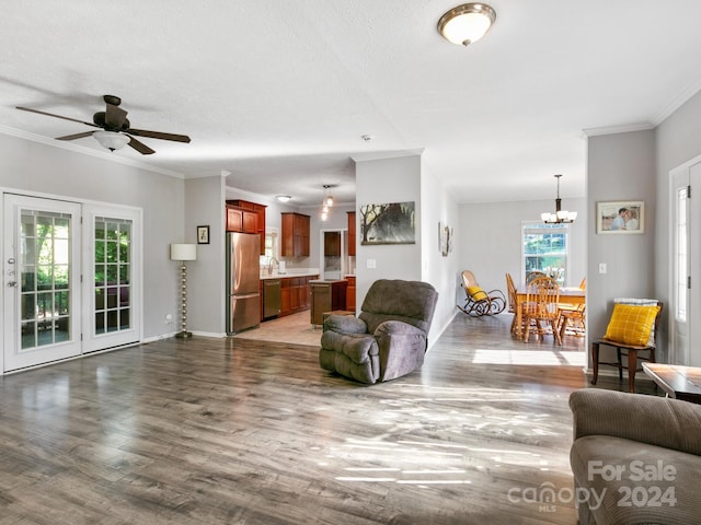 living room featuring hardwood / wood-style floors, ceiling fan with notable chandelier, and ornamental molding