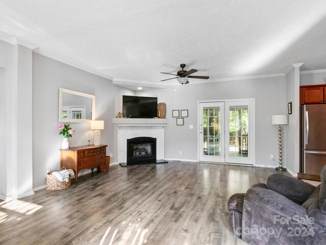 living room with hardwood / wood-style floors, crown molding, ceiling fan, and a fireplace