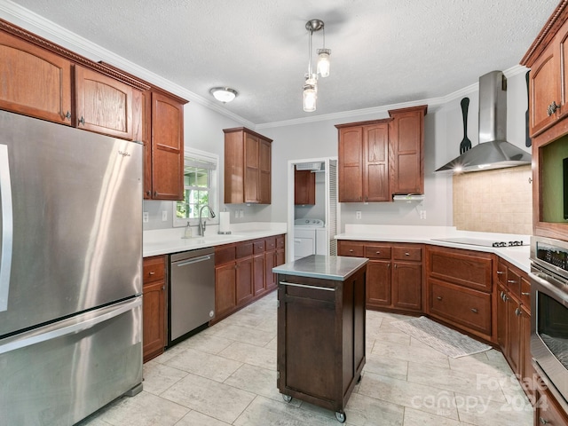 kitchen featuring wall chimney range hood, a kitchen island, washing machine and dryer, light tile patterned flooring, and stainless steel appliances