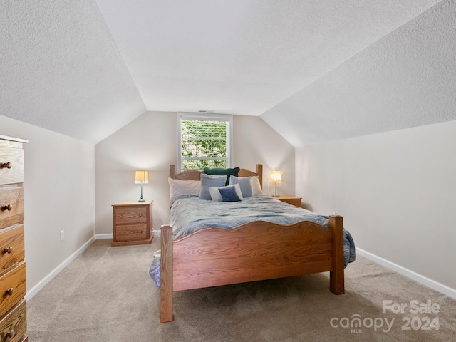 carpeted bedroom with a textured ceiling and lofted ceiling