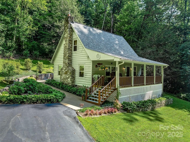 view of front of house featuring a chimney, a front lawn, a porch, and roof with shingles