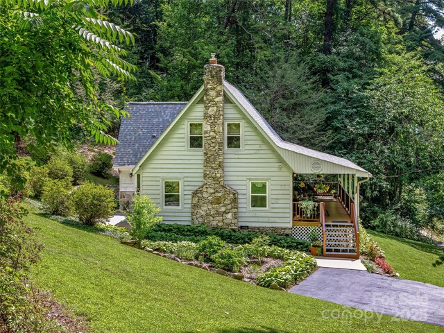 view of front of property featuring stairs, roof with shingles, a front lawn, and a chimney