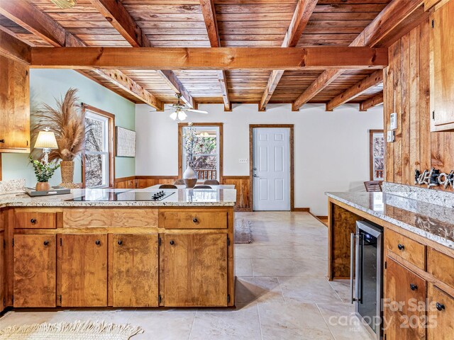 kitchen featuring beam ceiling, a wainscoted wall, wooden ceiling, beverage cooler, and a peninsula