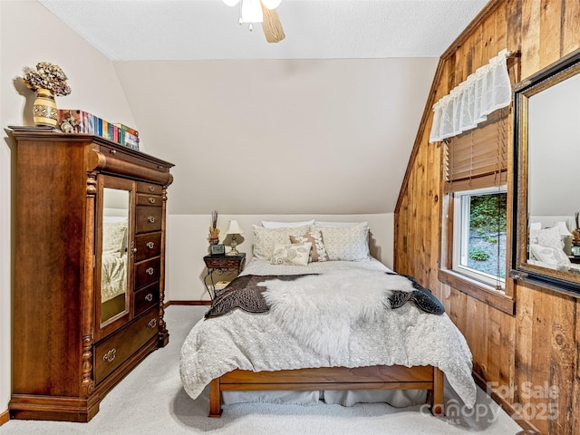 carpeted bedroom featuring vaulted ceiling, a textured ceiling, and a ceiling fan