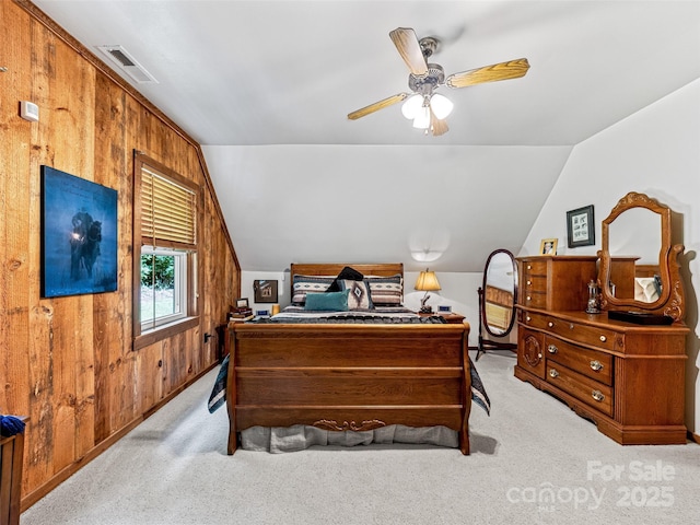 bedroom featuring light carpet, vaulted ceiling, visible vents, and wooden walls