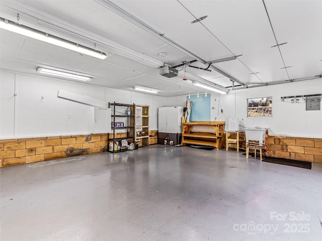 garage featuring concrete block wall and a garage door opener