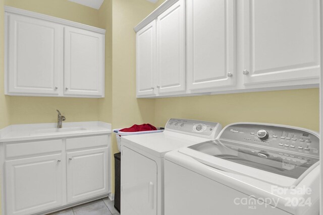 washroom featuring sink, washer and dryer, cabinets, and light tile patterned floors