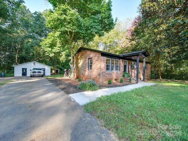 view of front of house featuring a front lawn, a garage, and an outbuilding