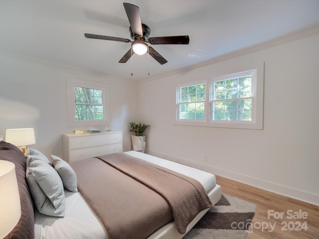 bedroom featuring light wood-type flooring, crown molding, and ceiling fan