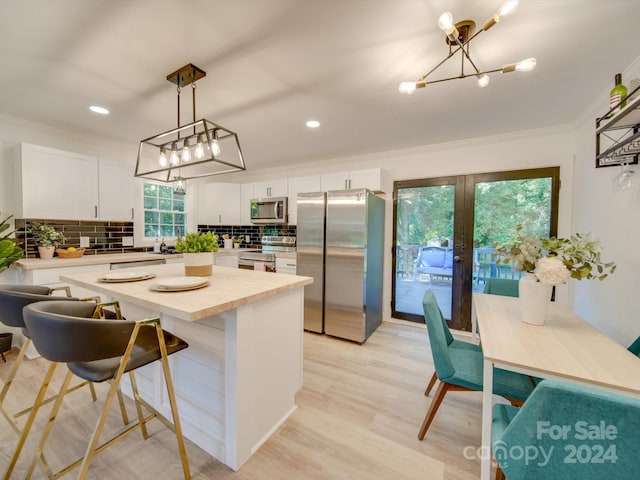 kitchen with decorative backsplash, white cabinetry, a healthy amount of sunlight, and stainless steel appliances