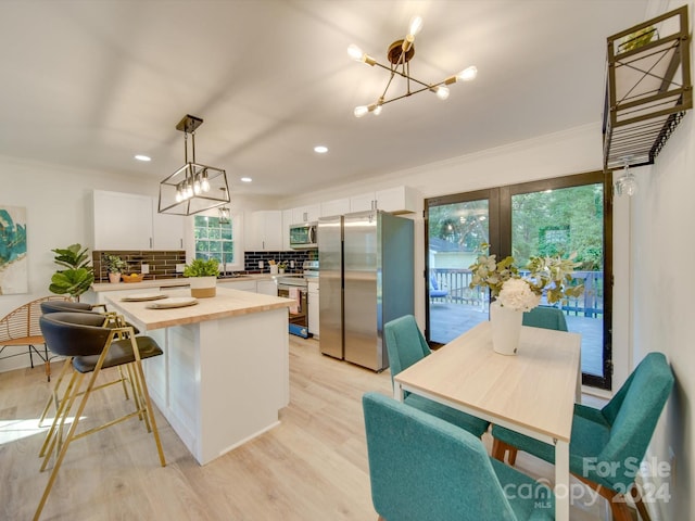 kitchen with light hardwood / wood-style flooring, backsplash, pendant lighting, white cabinets, and appliances with stainless steel finishes