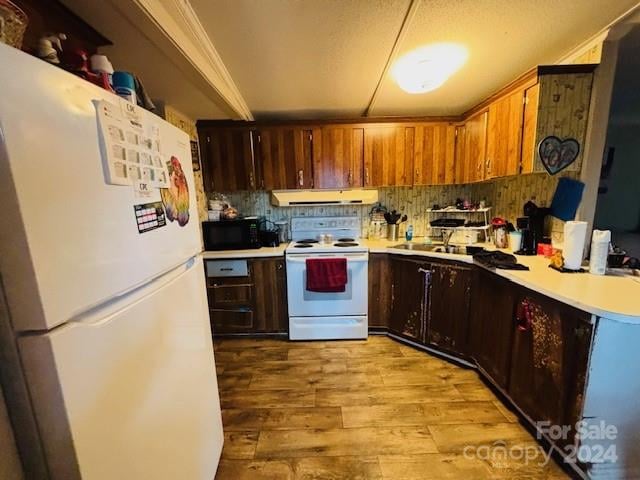 kitchen featuring backsplash, light hardwood / wood-style floors, white appliances, and crown molding