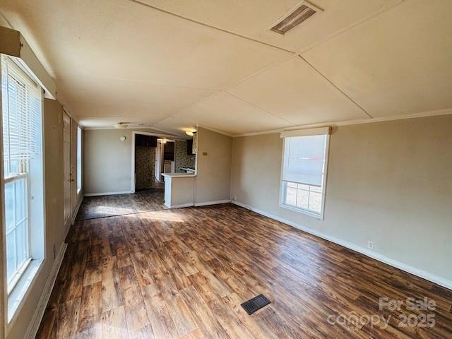 unfurnished living room with dark hardwood / wood-style flooring, crown molding, and vaulted ceiling