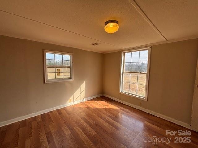 empty room featuring hardwood / wood-style flooring, plenty of natural light, and crown molding