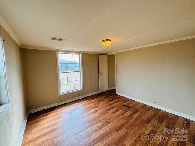 empty room with wood-type flooring and ornamental molding