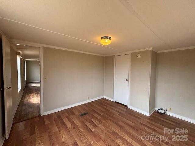 empty room featuring ornamental molding and dark hardwood / wood-style flooring