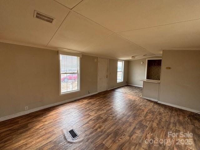 spare room featuring dark hardwood / wood-style flooring, crown molding, and lofted ceiling