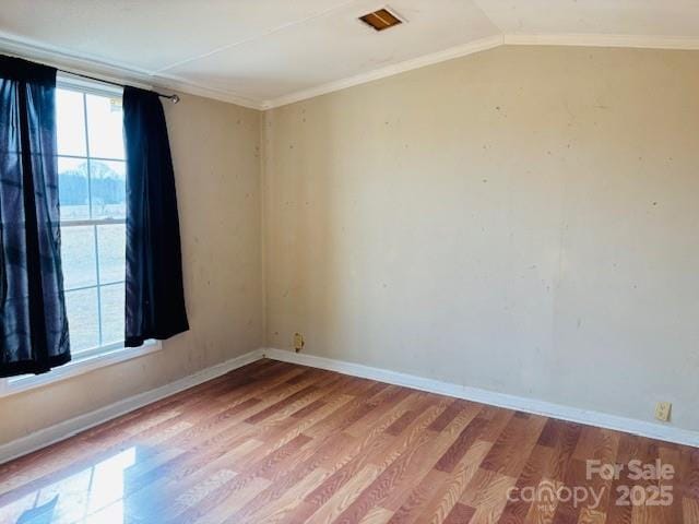 spare room featuring crown molding, plenty of natural light, light hardwood / wood-style floors, and vaulted ceiling