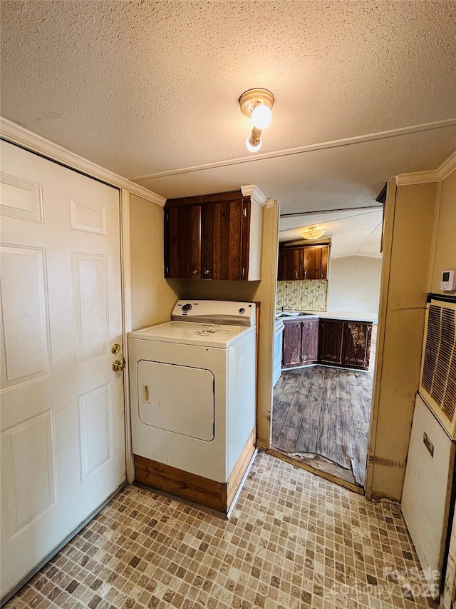 washroom featuring washer / clothes dryer, ornamental molding, a textured ceiling, and cabinets