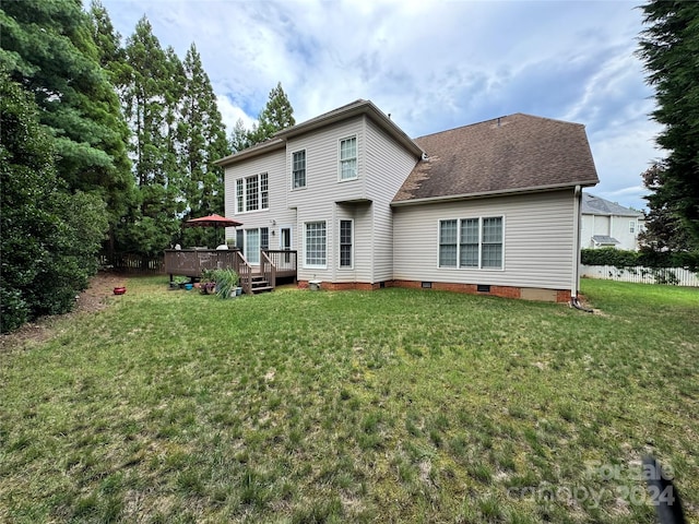 rear view of house featuring a deck and a lawn