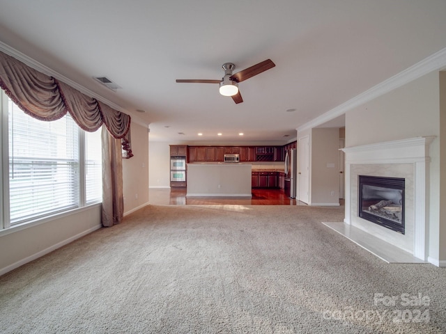 unfurnished living room featuring a fireplace, carpet floors, crown molding, and ceiling fan