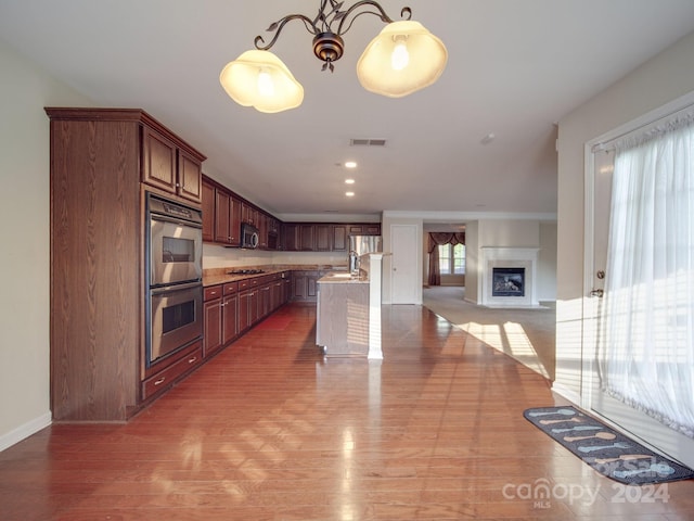 kitchen with light hardwood / wood-style flooring, hanging light fixtures, a kitchen bar, a center island, and stainless steel appliances