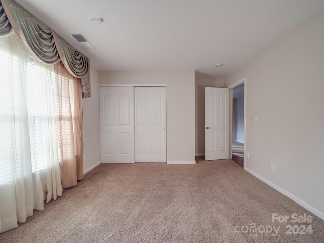 unfurnished bedroom featuring a closet and light colored carpet