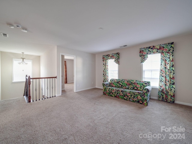 unfurnished room featuring carpet flooring, plenty of natural light, and an inviting chandelier