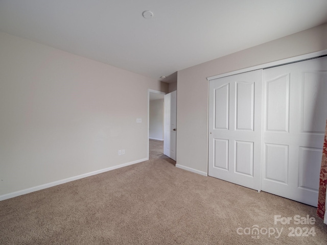 unfurnished bedroom featuring a closet and light colored carpet