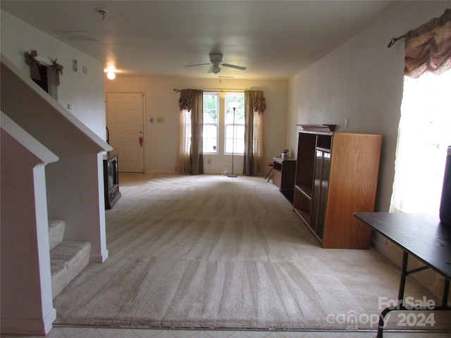 interior space with ceiling fan, light colored carpet, and a fireplace