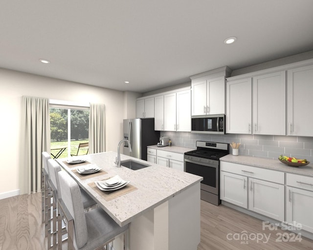 kitchen with stainless steel appliances, an island with sink, white cabinets, a breakfast bar, and sink