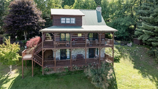 view of front of property with stone siding, a chimney, metal roof, a deck, and a front lawn