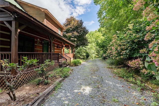 view of side of home with covered porch and gravel driveway