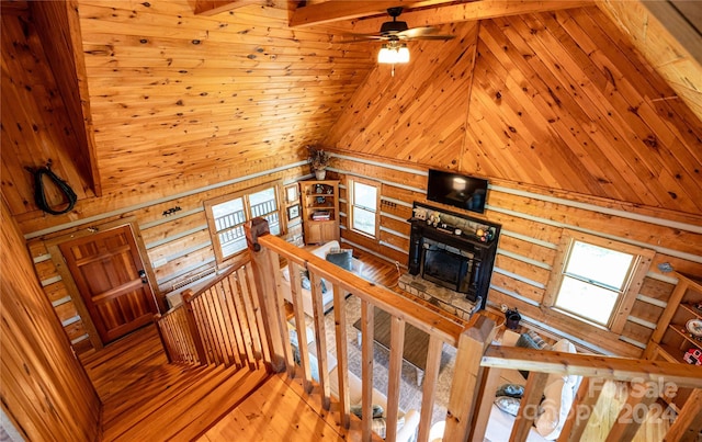 stairway featuring a ceiling fan, hardwood / wood-style floors, beamed ceiling, a fireplace, and high vaulted ceiling