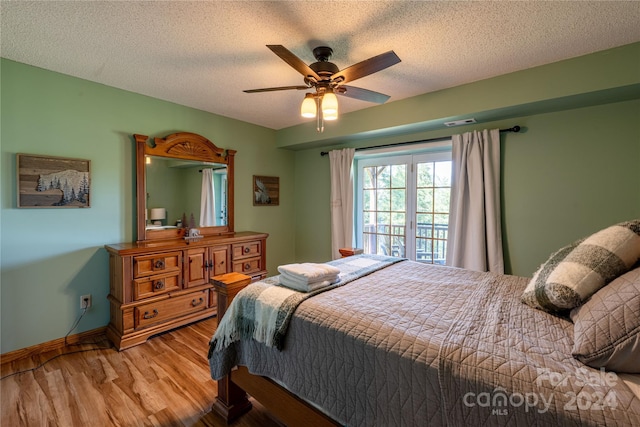 bedroom featuring a ceiling fan, a textured ceiling, baseboards, and wood finished floors