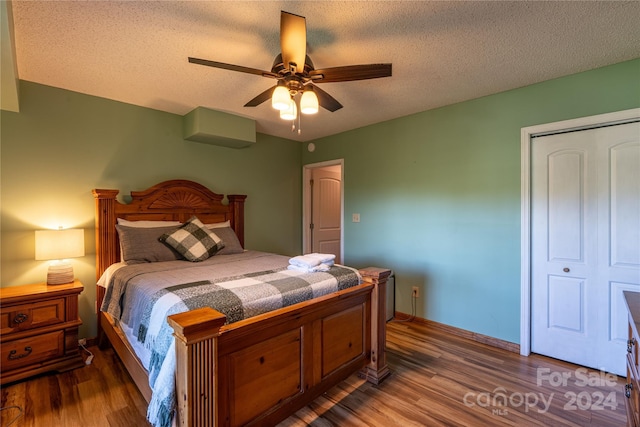 bedroom featuring a ceiling fan, a textured ceiling, baseboards, and wood finished floors