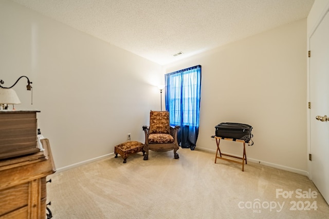 living area featuring light colored carpet, visible vents, a textured ceiling, and baseboards